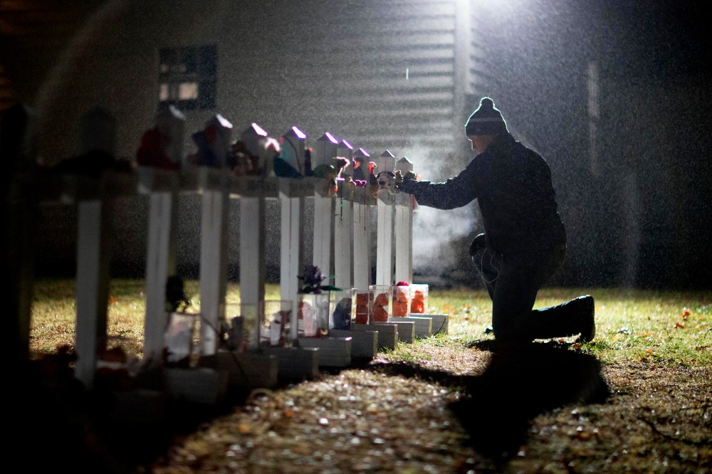 A man adjusts a display of wooden crosses, and a Jewish Star of David, representing the victims of the Sandy Hook Elementary School shooting, on his front lawn, Dec. 17, 2012, in Newtown, Conn. (Photo by David Goldman/AP)