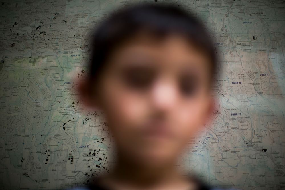 A Guatemalan child deported from the United State poses for photo in front of a map of the Guatemala City at an immigration shelter, June 19, 2014.