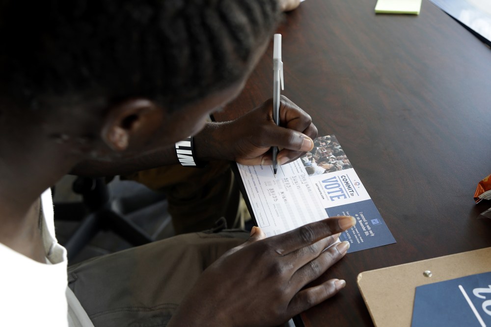 Dehjahn Swain, 19, signs a Commit To Vote card after registering to vote, Oct. 8, 2012 in Miami, Fla.