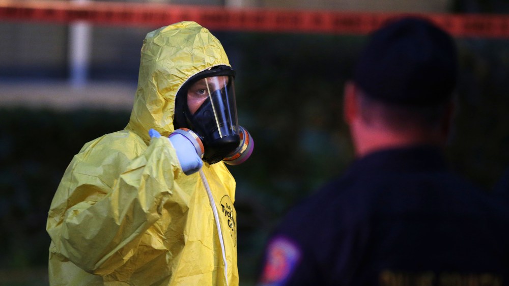 A hazmat worker looks up while finishing up cleaning outside an apartment building of a hospital worker, Oct. 12, 2014, in Dallas, Texas. (Photo by LM Otero/AP)