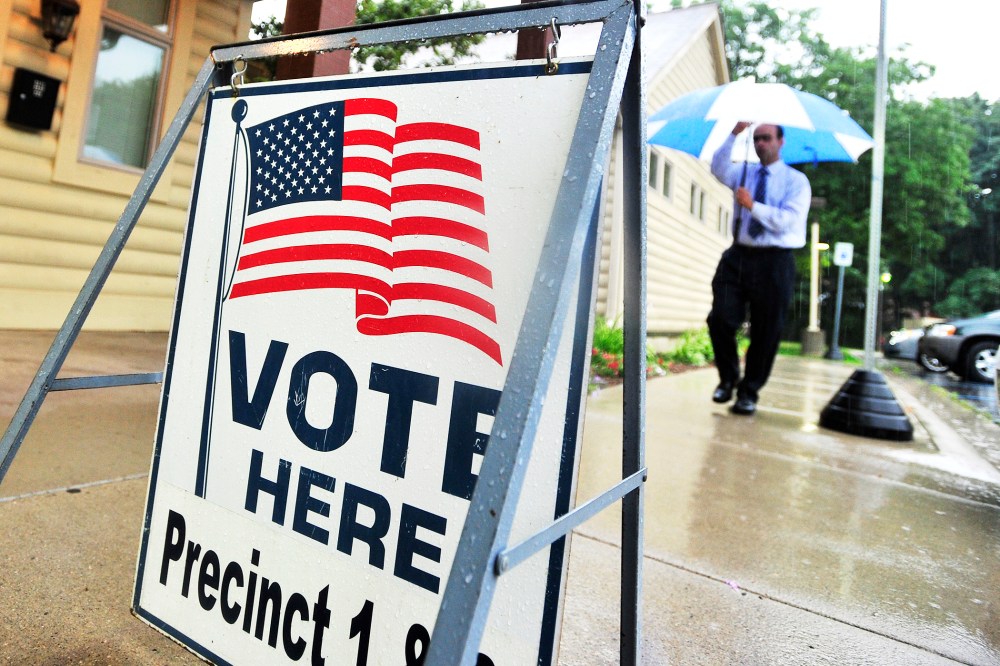 A man walks in the rain to vote at the Rochester Community House in Rochester, Mich. on Tuesday, Aug. 5, 2014.