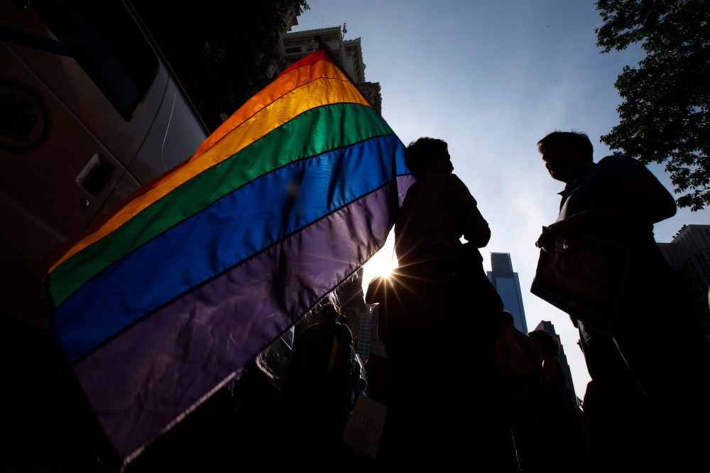 A person holds a gay pride flag during a rally. (Photo by Matt Slocum/AP)