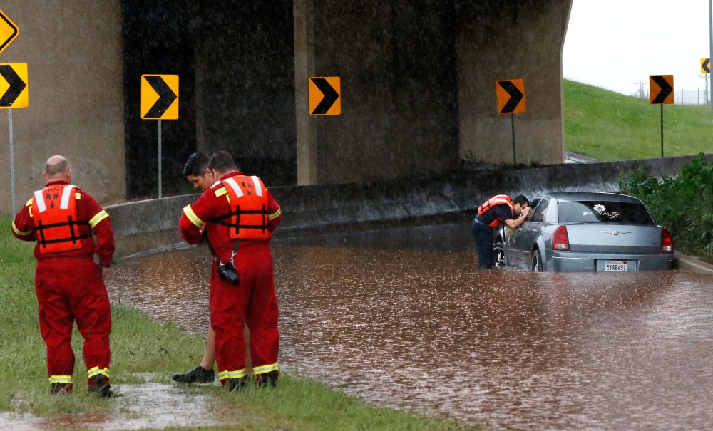 A firefighter looks into the window of a partially submerged car, checking to see if anyone is inside, May 23, 2015, in Oklahoma City. (Photo by Jim Beckel/The Oklahoman/AP)