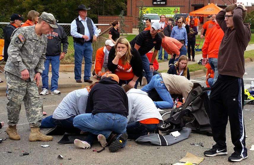 Bystanders help the injured after a vehicle crashed into a crowd of spectators during the Oklahoma State University homecoming parade, causing multiple injuries, Oct. 24, 2015 in Stillwater, Oka. (Photo by David Bitton/The News Press/AP)