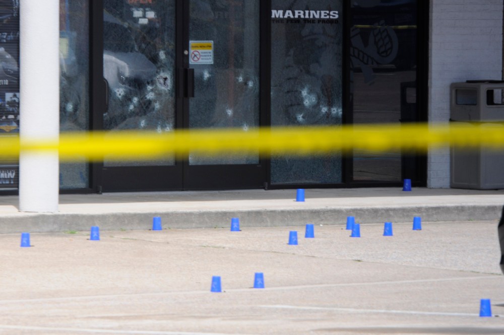 The windows of the Armed Forces Recruitment Center have several bullet holes from a shooting as the area is cordoned off with blue shell casing markers in the parking lot, July 16, 2015 in Chattanooga, Tenn. (Tim Barber/Chattanooga Times Free Press/AP)
