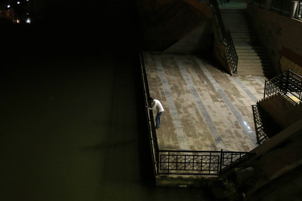 In this Oct. 22, 2015, photo, Daniel Halaby, a gay Syrian man who fled from the Islamic State group, looks at his mobile phone as he stands along a riverbank in southern Turkey. (Photo by Hussein Malla/AP)