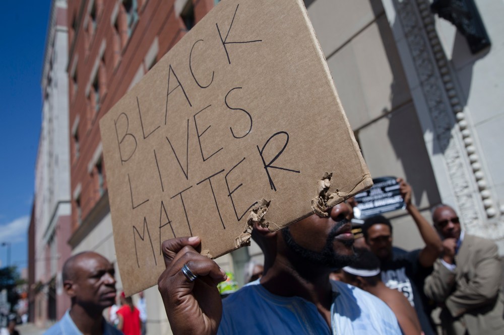 Demonstrators hold signs outside the office of Hamilton County prosecutor Joe Deters' office during a protest demanding release of video showing the shooting death of Samuel Dubose on July 23, 2015, in Cincinnatti, Ohio. (Photo by John Minchillo/AP)