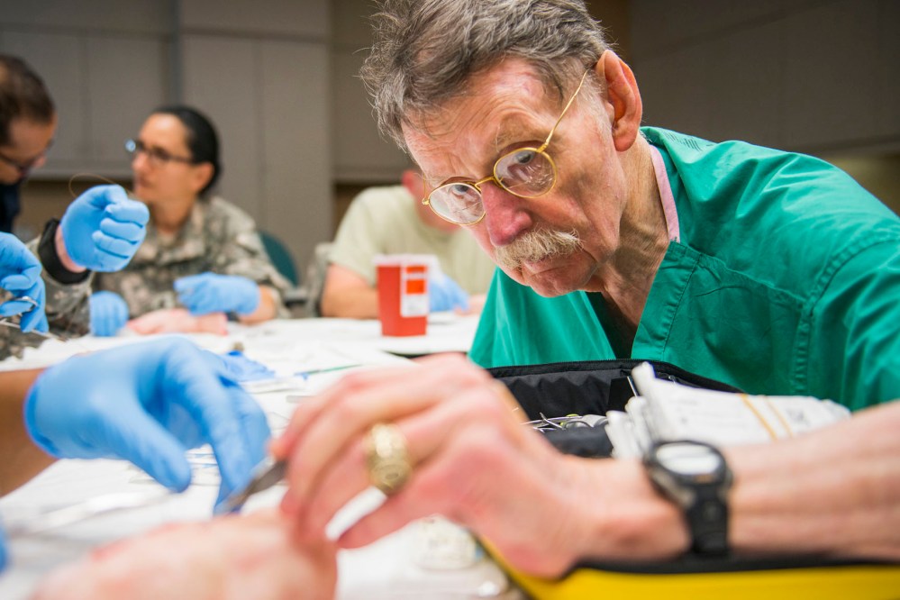 Dr. James "Red" Duke instructs a group of U.S. Army flight medics in suturing techniques using pigs feet at Memorial Hermann Hospital in Houston, Texas on Aug. 15, 2013. (Photo by Smiley N. Pool/Houston Chronicle/File/AP)