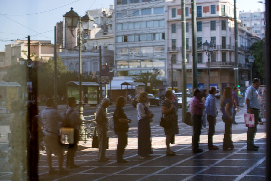 People are seen reflected at a glass of a bank as they line up to withdraw cash from a bank machine in central Athens, Greece, July 8, 2015. (Photo by Emilio Morenatti/AP)