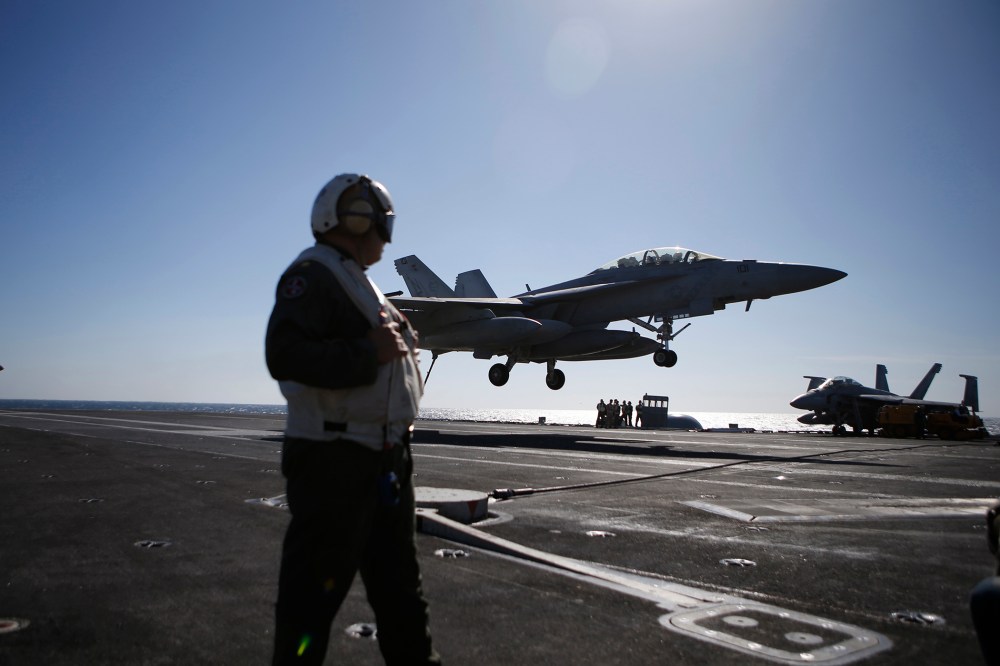 A U.S. Navy crew member looks at an F/A-18 Super Hornet fighter landing onto the deck of the USS Ronald Reagan, during a joint naval drill between South Korea and the U.S. in the West Sea, South Korea, Oct. 28, 2015. (Photo by Kim Hong-ji/Pool/AP)