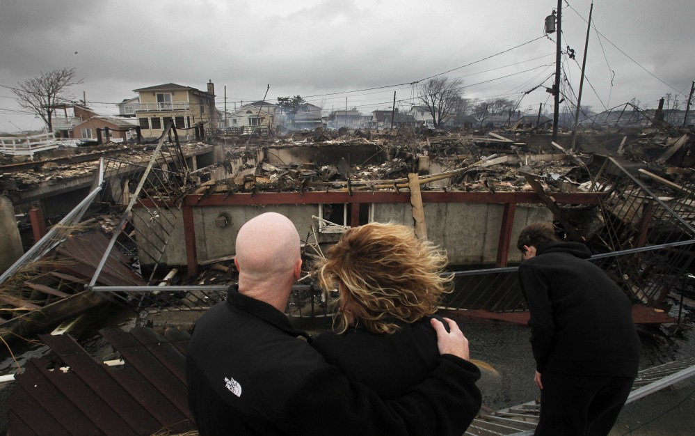 Robert Connolly, left, embraces his wife Laura as they survey the remains of the home owned by her parents that burned to the ground in the Breezy Point section of New York, Tuesday, Oct. 30, 2012. More than 50 homes were destroyed in the fire which...