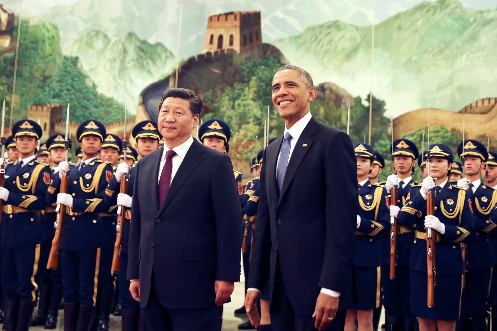 U.S. President Barack Obama, right, smiles after a group of children waved flags and flowers to cheer him during a welcome ceremony with Chinese President Xi Jinping at the Great Hall of the People in Beijing, China, Nov. 12, 2014. (Photo by Andy Wong/AP)