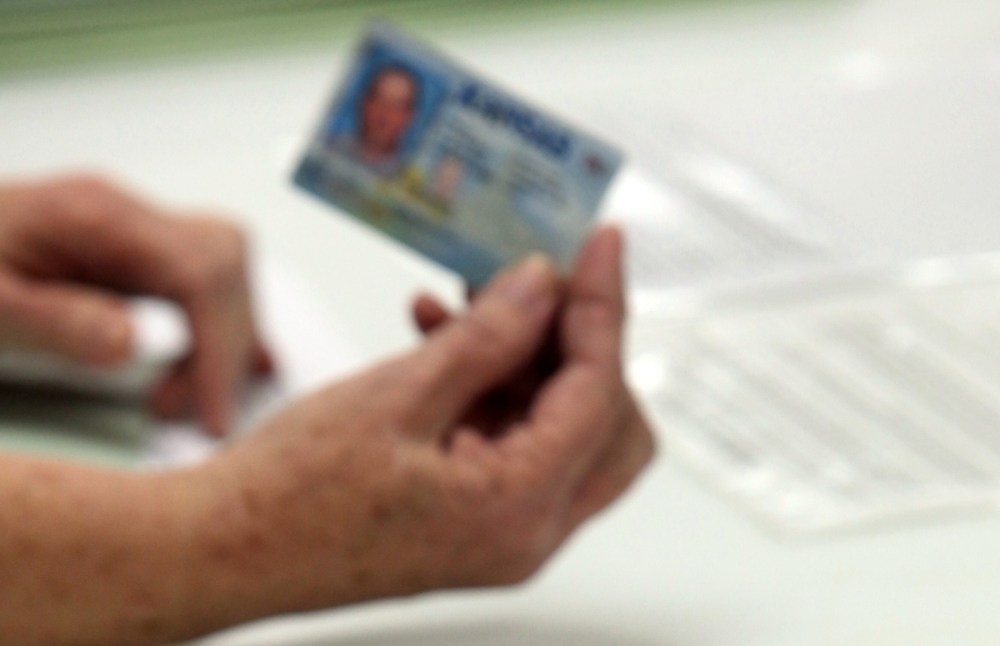 FILE - In this Jan. 10, 2012 file photo, election officials check the photo identification card of a voter in Cimarron, Kan. Voter ID laws designed to deter fraud may end up blocking thousands of legitimate ballots.  (AP Photo/The The Hutchinson News,...