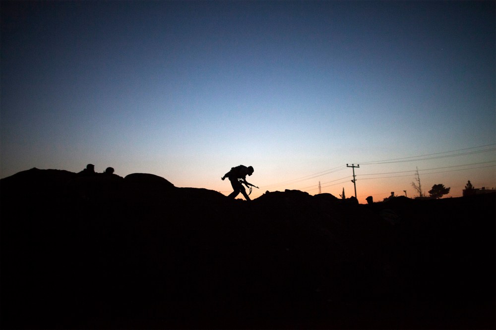 The silhouette of an armed fighter of the Committees for the Protection of the Kurdish People (YPG) is seen as runs to take position along the front line on October 16, 2013 in the Syrian town of Ras al-Ain, close to the Turkish border.