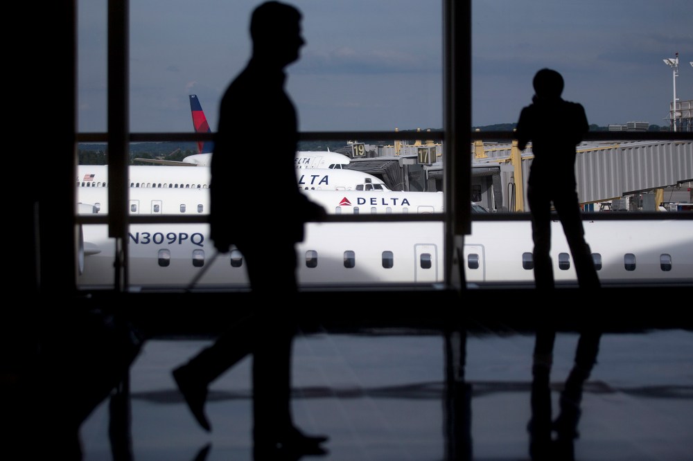 The silhouettes of a travelers are seen walking past Delta Air Lines airplanes parked at gates of Ronald Reagan National Airport in Washington, D.C. (Photo by Andrew Harrer/Bloomberg/Getty)