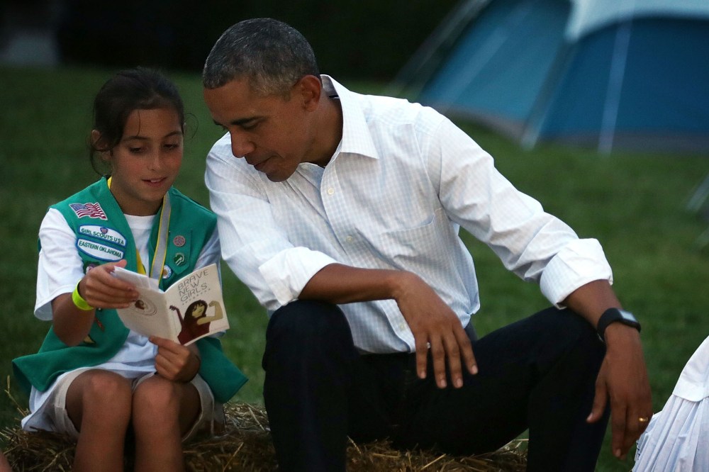 Daphnye Shell reads a book with U.S. President Barack Obama during a campfire songs session at the first-ever White House Campout (Photo by Alex Wong/Getty).