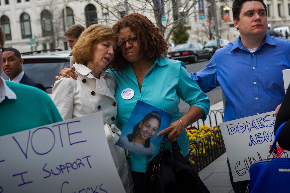 Relatives of victims of notable shootings comfort one another during a protest outside the National Shooting Sports Foundation's annual Congressional Fly-In fundraising dinner April 2, 2014, in Washington, DC. (Photo by Rod Lamkey/Getty)