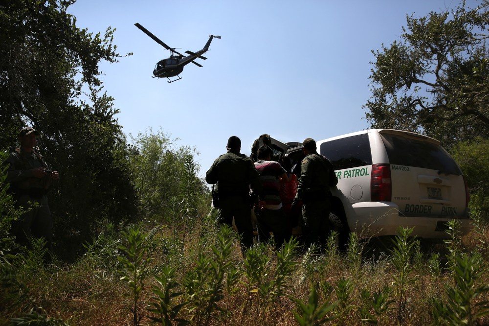 U.S. Border Patrol agents detain undocumented immigrants north of the U.S.-Mexico border on Aug. 6, 2015 near Falfurrias, Texas. (Photo by John Moore/Getty)