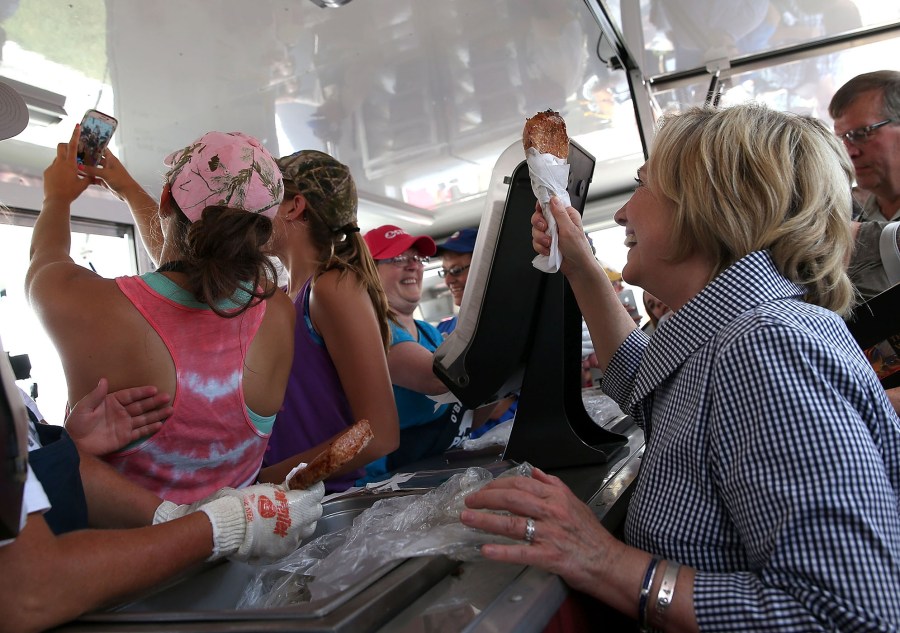 Democratic presidential hopeful Hillary Clinton holds a Pork Chop on a Stick as she takes a selfie with booth worker while touring the Iowa State Fair, Aug. 15, 2015 in Des Moines, Ia. (Photo by Justin Sullivan/Getty)