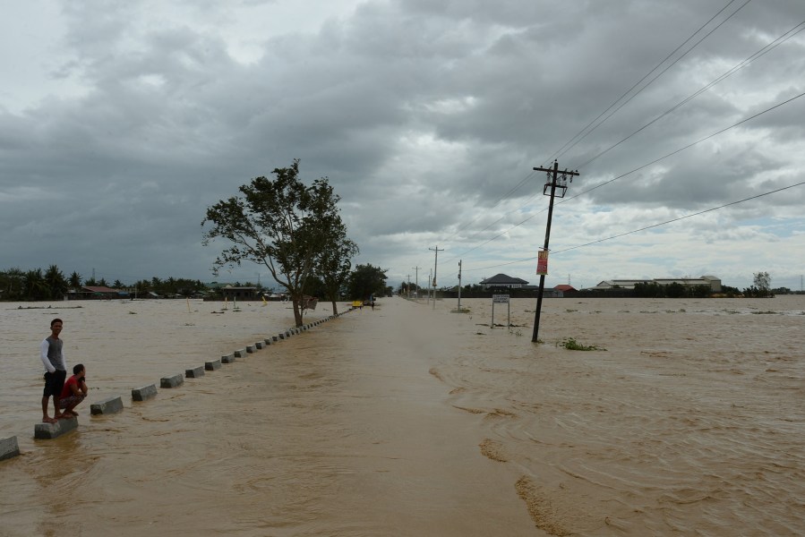 Residents stand on a flooded highway in Santa Rosa town, Nueva Ecija province, north of Manila on Oct. 19, 2015, a day after typhoon Koppu hit Aurora province. (Photo by Ted Aljibe/AFP/Getty)