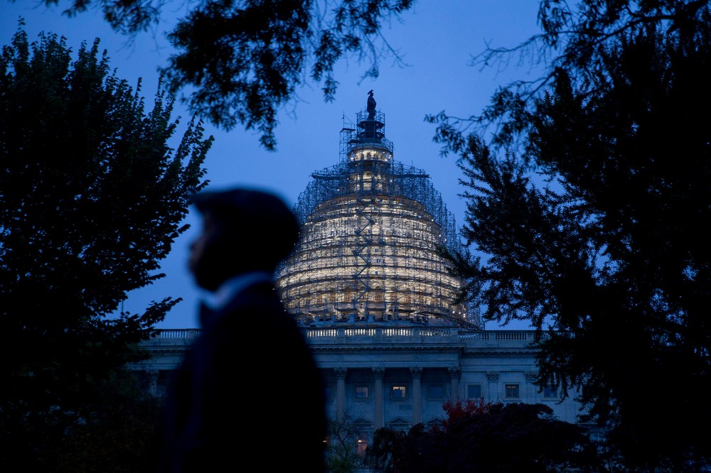 The U.S. Capitol building surrounded by scaffolding as someone walks by on Oct. 28, 2015, in Washington, D.C. (Photo by Andrew Harrer/Bloomberg/Getty)