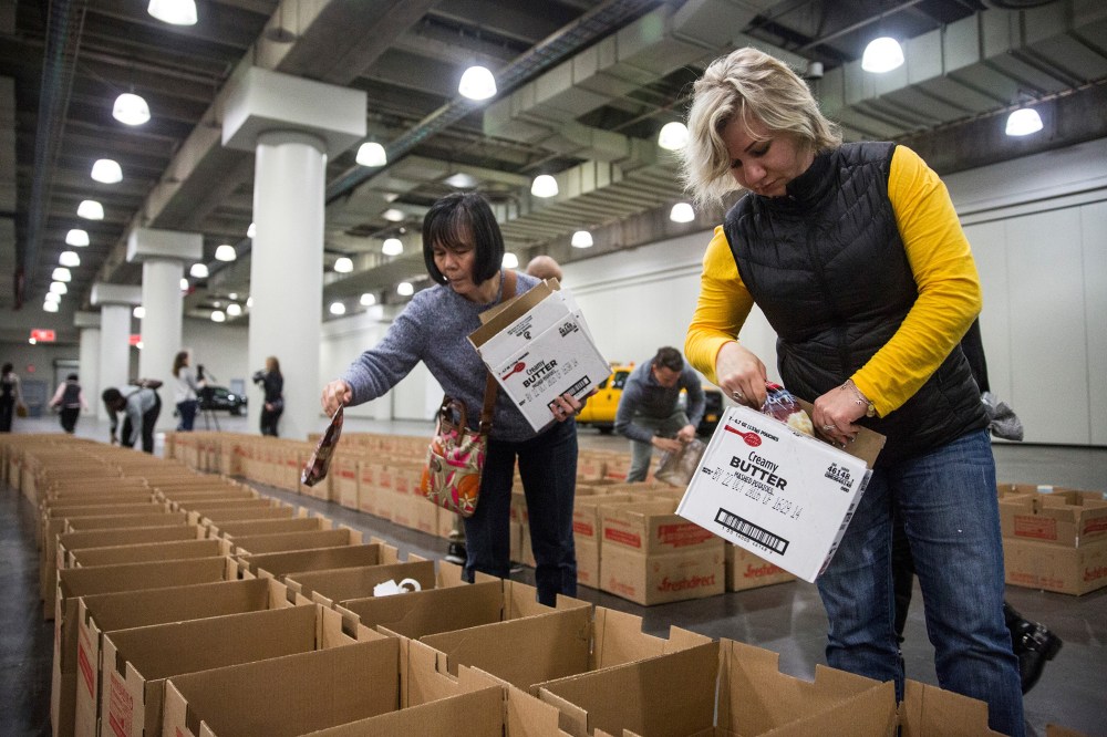 Volunteers distribute donated food into Thanksgiving meal boxes on Nov. 23, 2015 in New York City. The free meals were organized by the state government through a food drive and given to those in need for Thanksgiving. (Photo by Andrew Burton/Getty)