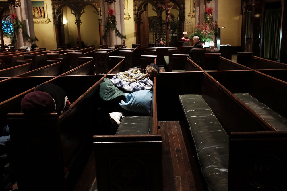 A homeless man sleeps in the warmth of a church in midtown Manhattan after a recent cold spell on Jan. 5, 2016 in New York City. (Photo by Spencer Platt/Getty)