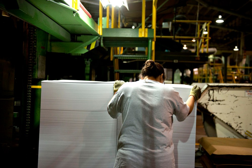 An employee guides a stack of cut paper as it is unloaded from a cutting machine at a paper mill in Rothschild, Wisconsin, U.S., on Wednesday, Oct. 10, 2012.