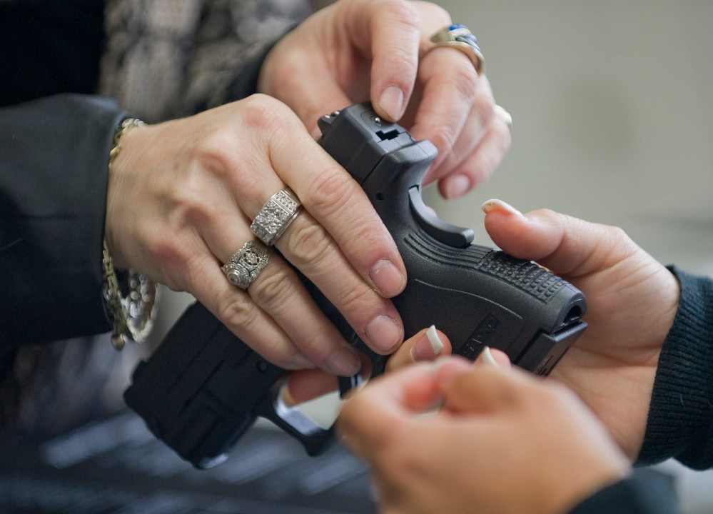 At Ade's Gun Shop & Em & M Guns in Orange, Emily Atkinson shows the safety features of a Springfield Armory XD compact pistol to a female client on Dec. 6, 2012.(AP Photo/The Orange County Register, Jebb Harris)