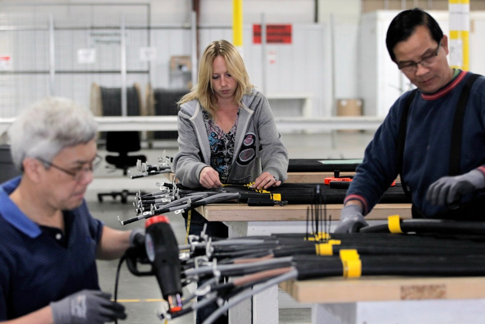 In this Nov. 2, 2012 photo, Jenifer Zeleny, center, does a quality-control inspection, as workers manufacture cables used in wind turbines, inside the production area at the Walker Components factory, in Denver. One-third of the workers at the factory...