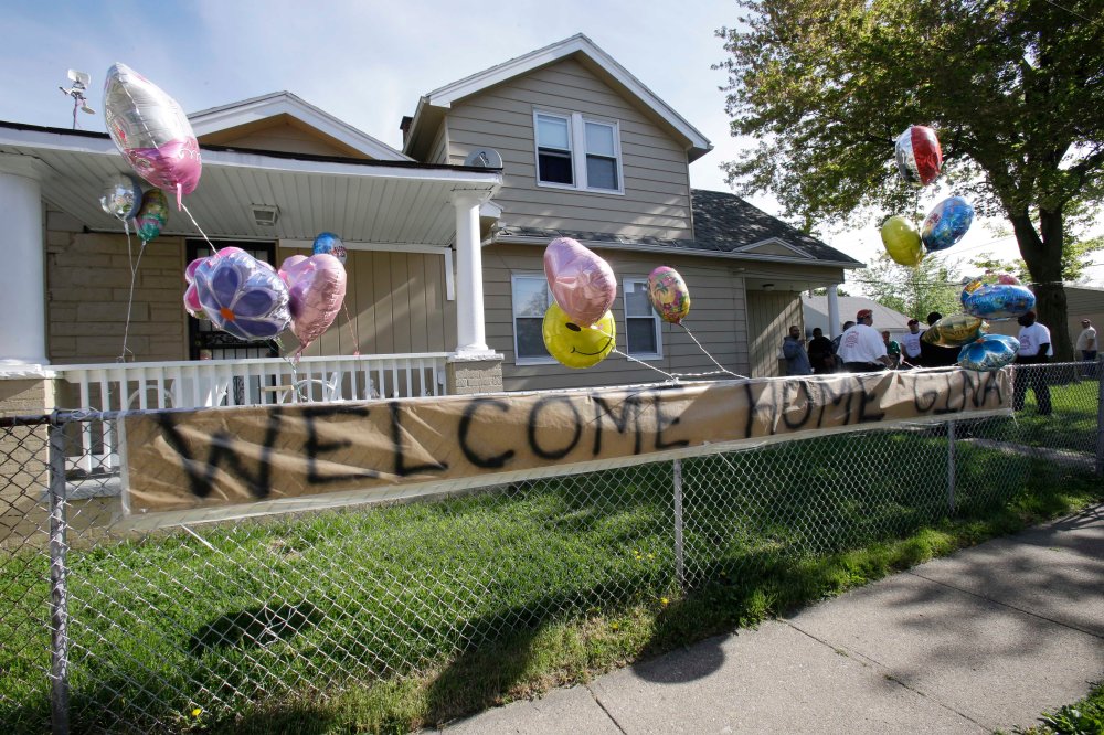 A "Welcome Home Gina " sign hangs on a fence outside the home of Gina DeJesus Tuesday, May 7, 2013, in Cleveland. DeJesus, Amanda Berry and Michelle Knight, who went missing separately about a decade ago, were found in a home just south of downtown...