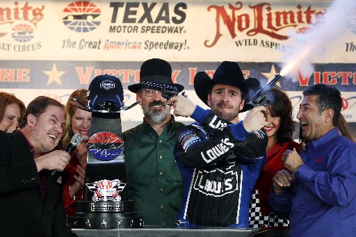 Track President Eddie Gossage, left, ducks as Jimmie Johnson fires blanks out of a revolver while celebrating in victory lane following his win in the NASCAR Sprint Cup Series auto race at Texas Motor Speedway, Sunday, Nov. 4, 2012, in Fort Worth,...