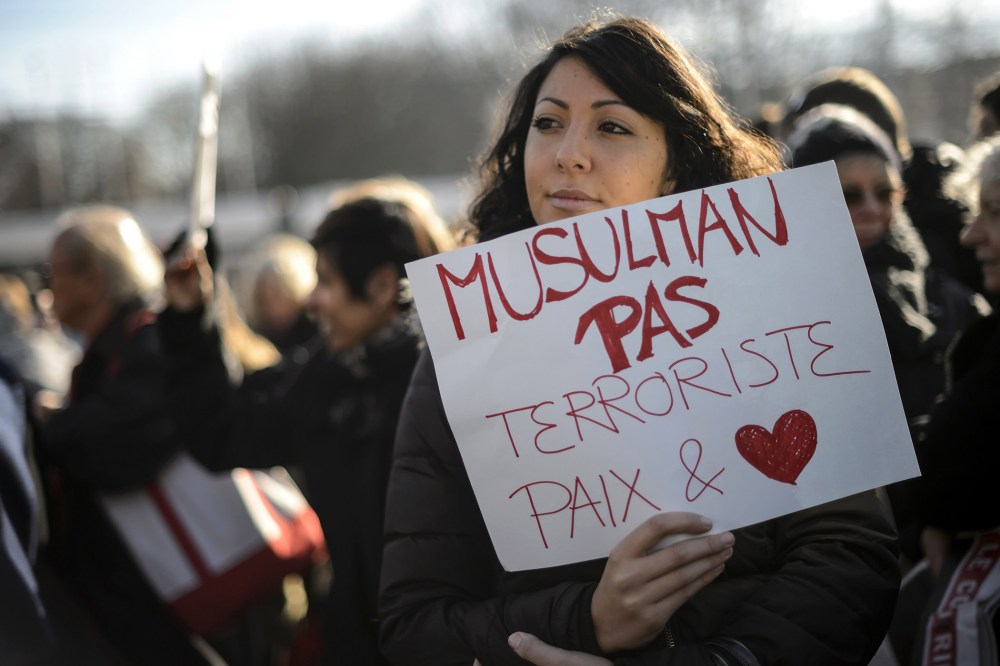 A woman hold a placard reading in French "Muslim not terrorists, peace and love" during a gathering in the center of Geneva on Jan. 8, 2015 to pay tribute to the twelve people killed the day before in an attack by two armed gunmen on the offices of Fre