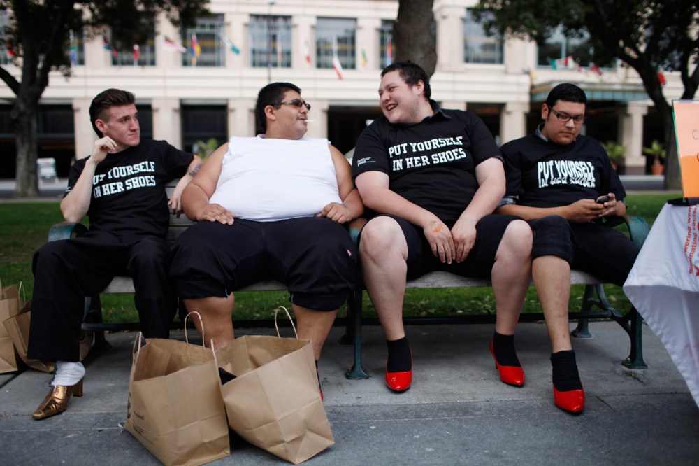 Bill Kincaid (L-R), Antonio Ayala, Robert Barrientos, and Chuy Jimenez share a bench while wearing women's high heels during the 10th annual Walk A Mile In Her Shoes to raise awareness against sexual violence in Plaza De Cesar Chavez in San Jose,...
