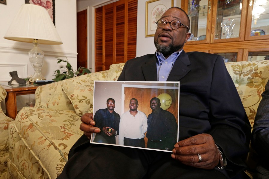 Anthony Scott holds a photo of himself, center, and his brothers Walter Scott, left, and Rodney Scott, right, as he talks about his brother at his home near North Charleston, S.C., on April 8, 2015.