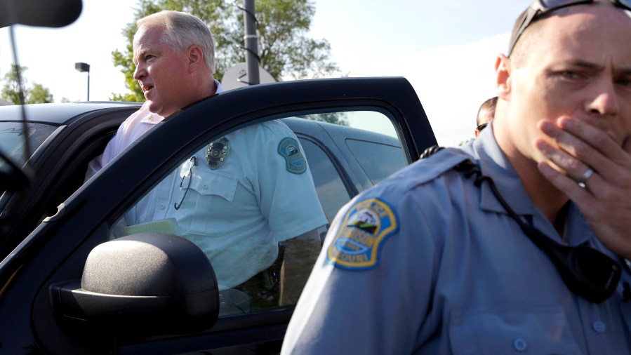 Ferguson Police Chief Thomas Jackson, left, gets in a vehicle to drive away after a news conference on Aug. 15, 2014, in Ferguson, Mo.