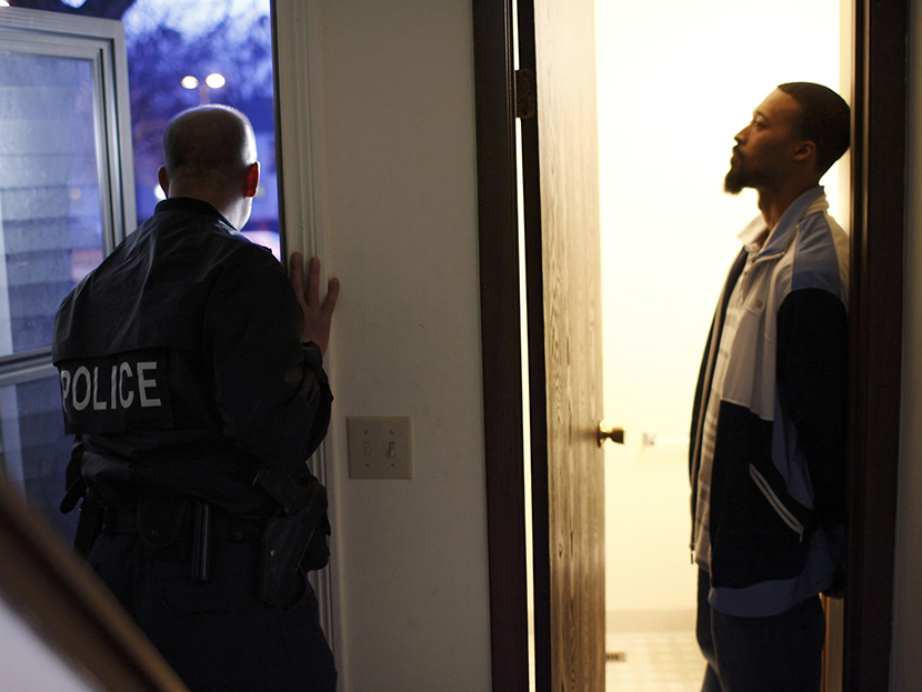 Suspect Gerald Ware (R) stands handcuffed in the doorway of his home as police conduct a raid in search of illegal drugs during the execution of a search warrant for marijuana in Kalamazoo, Michigan, on November 12, 2009 file picture.  (Photo by John...