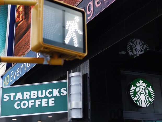 A walk sign flashes in Times Square in front of a store bearing the new Starbucks logo in New York