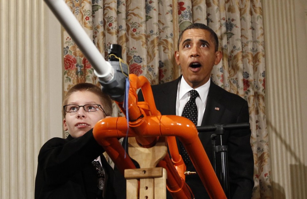President Barack Obama reacts as Joey Hudy of Phoenix, Arizona, launches a marshmallow from his Extreme Marshmallow Cannon in the State Dining Room of the White House during the second White House Science Fair in Washington February 7, 2012.