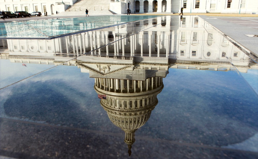 The dome of the Capitol is reflected in a puddle in Washington, Feb. 17, 2012.