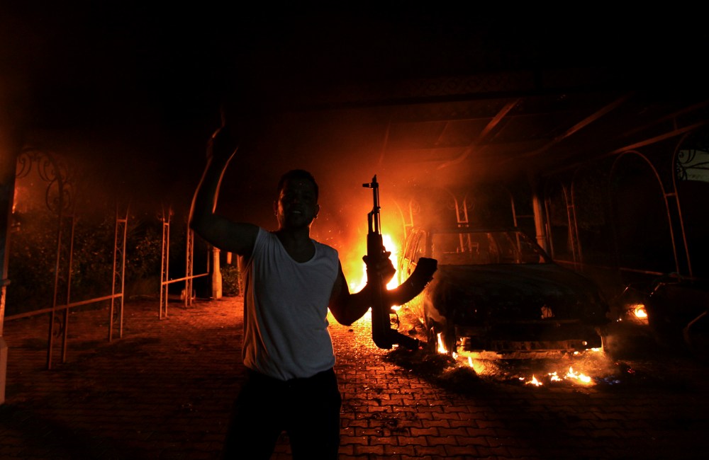 A protester reacts as the U.S. Consulate in Benghazi is seen in flames