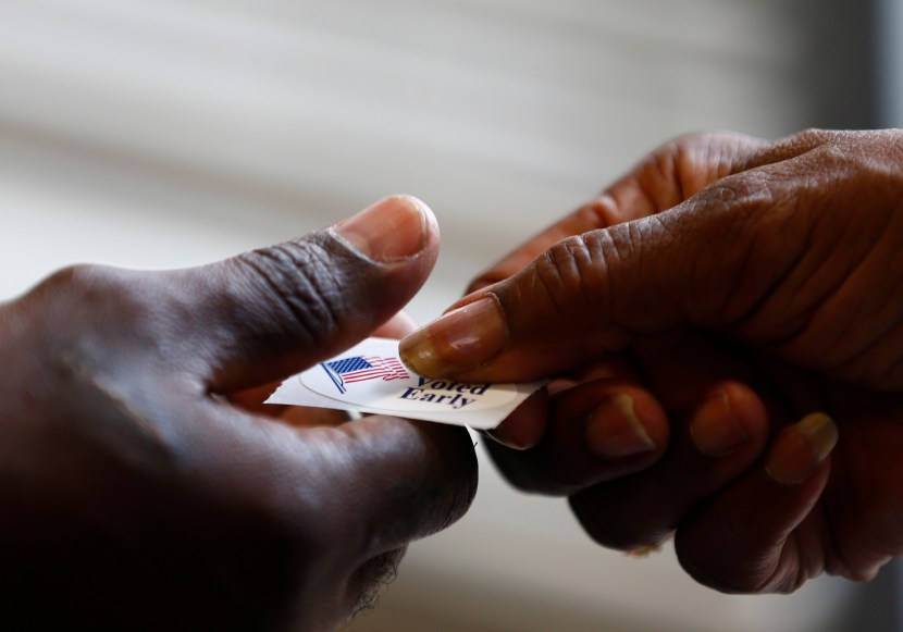 A poll worker hands a sticker to a voter at a polling place in Charlotte, North Carolina October 27, 2012. (Photo by Chris Keane/Reuters)