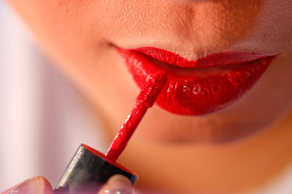 A woman applies applies red lipstick. (Photo by Athit Perawongmetha/Reuters)