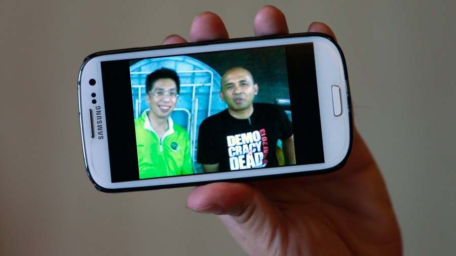 Peter Chong holds a smartphone displaying a picture of himself with missing Malaysia Airlines Flight MH370 captain Zaharie Ahmad Shah (R) during an interview with Reuters at a hotel in Sepang on March 18, 2014.