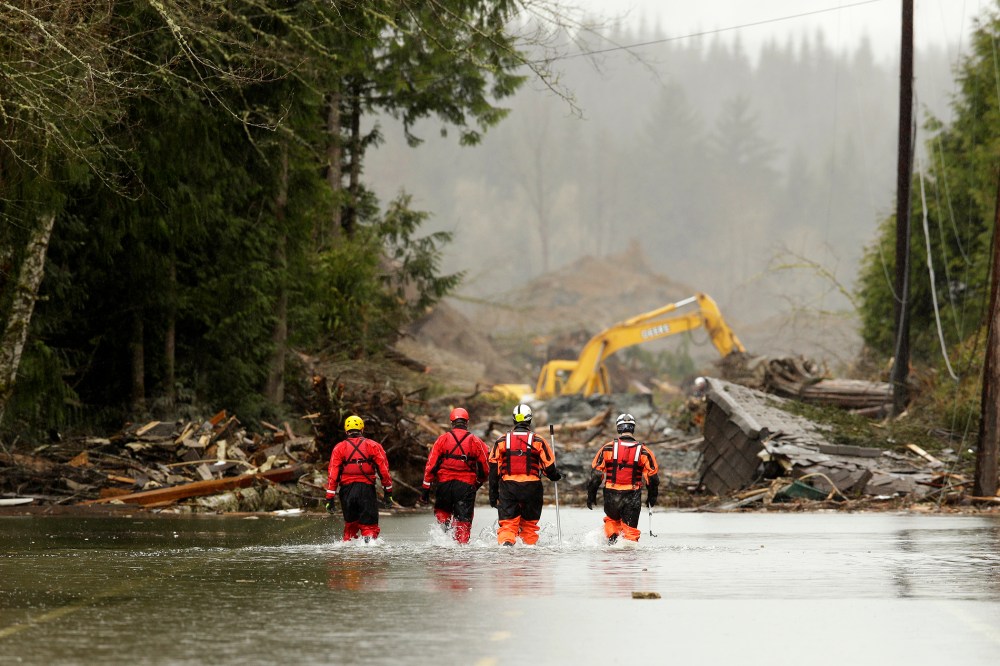 Rescuers walk in floodwaters on Highway 530 as search work continues in the mud and debris from a massive mudslide that struck Oso near Darrington, Washington, March 27, 2014.