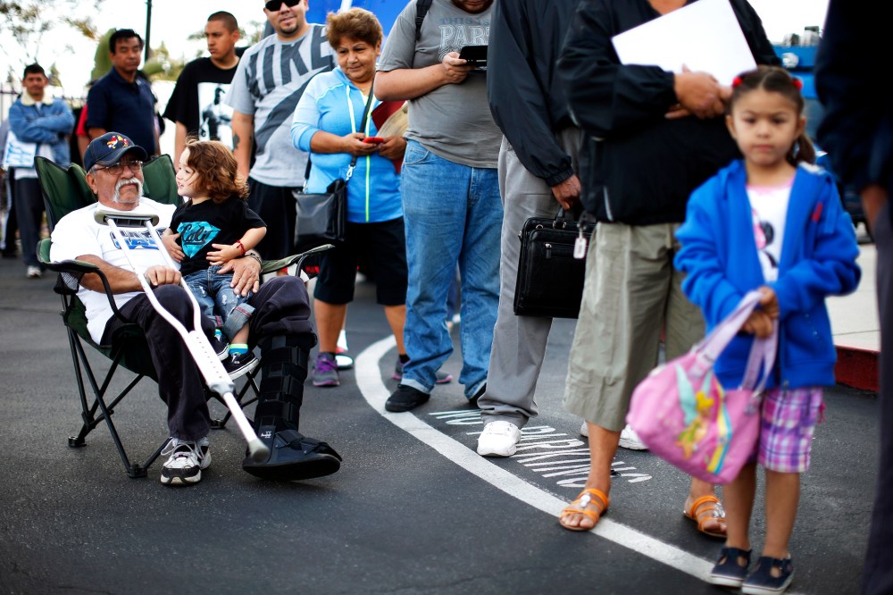 Juan Ortiz, 67, and his eighteen-month-old grandson Joshua Lopez wait in line at a health insurance enrolment event in Commerce, California, Mar. 31, 2014.
