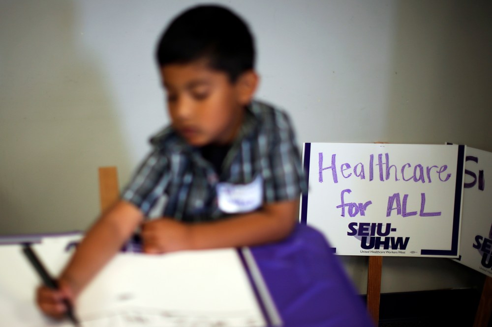 A boy draws signs at a health insurance enrollment event in Commerce, California March 31, 2014.