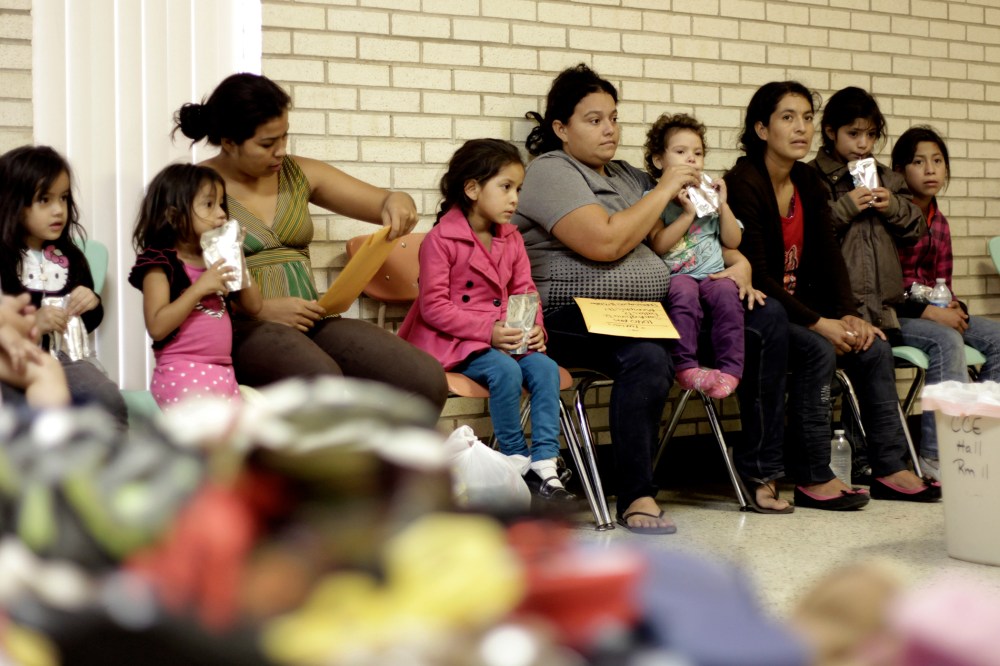 Migrants sit at the Sacred Heart Catholic Church temporary migrant shelter in McAllen, Texas