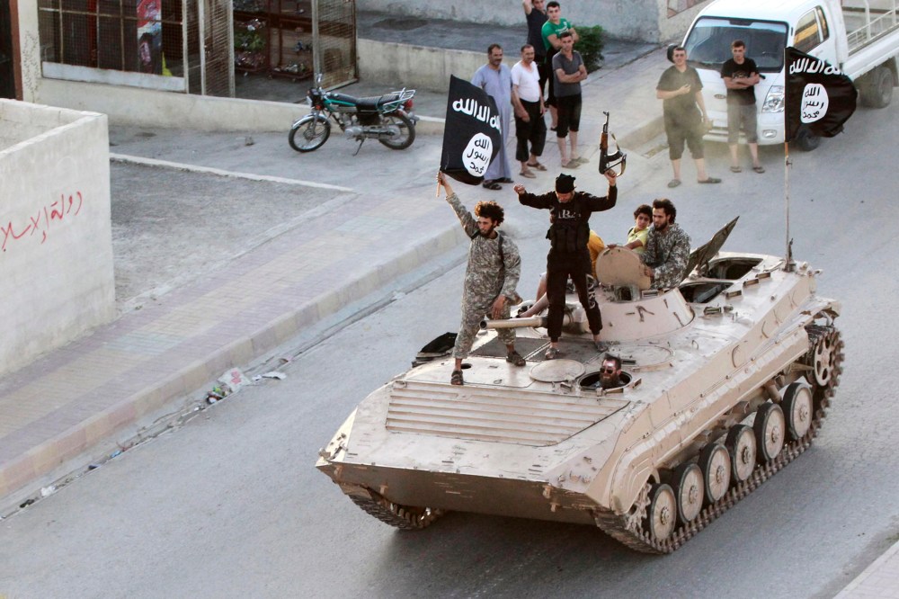 Militant Islamist fighters take part in a military parade along the streets of northern Raqqa province on June 30, 2014.