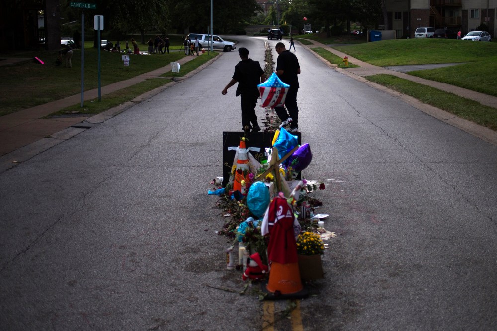 Men walk past a makeshift memorial near the site where unarmed teen Michael Brown was shot dead in Ferguson